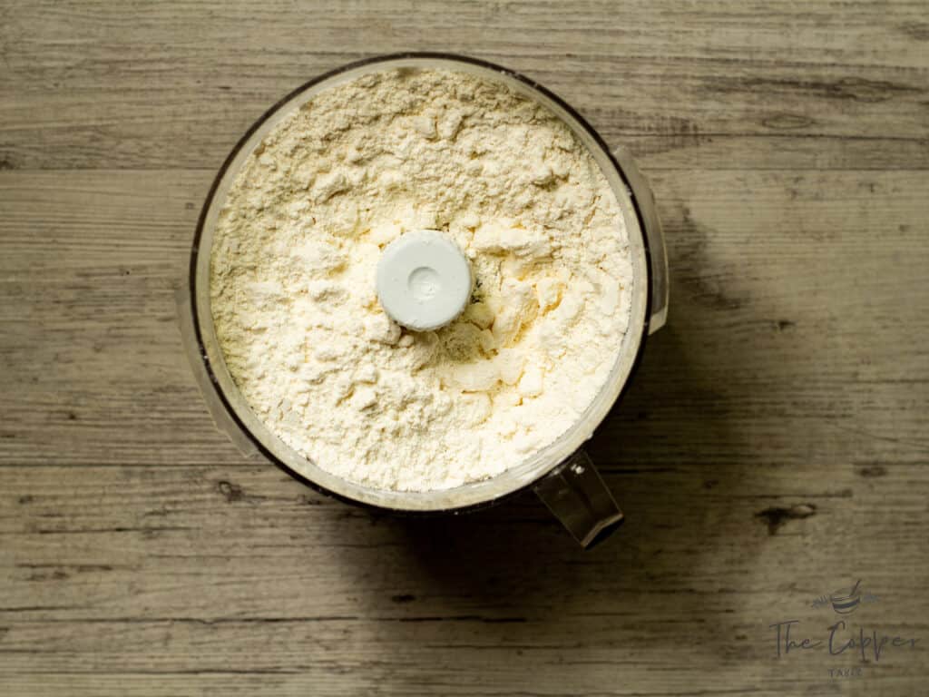 Flour and butter in a food processor after being pulsed