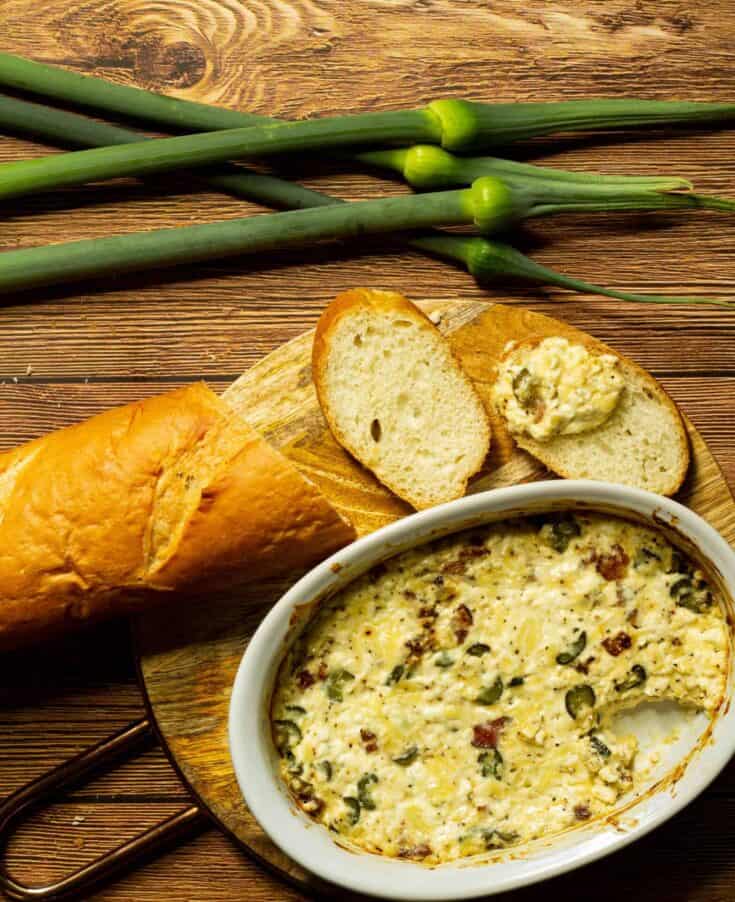 baguette on a board with a dish of leek scape dip