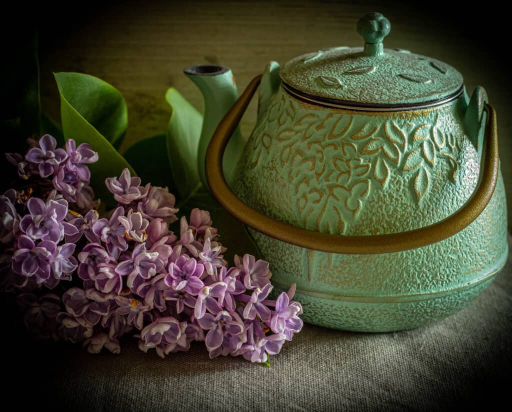 lilacs next to a green teapot