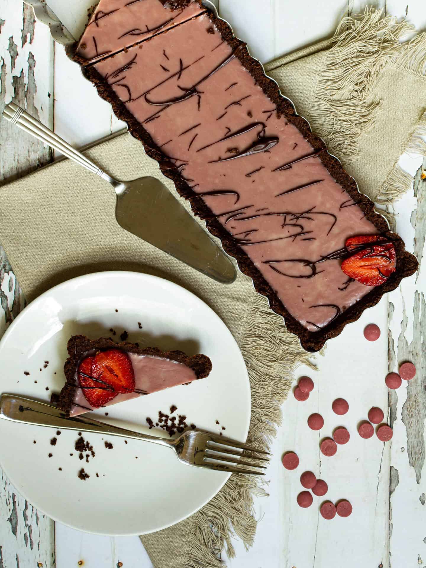 ruby chocolate tart next to a plate with a piece of tart