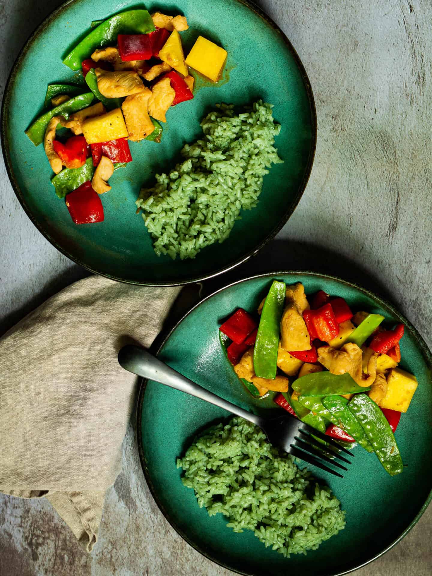 two green bowls of chicken and pineapple stirfry with bamboo rice