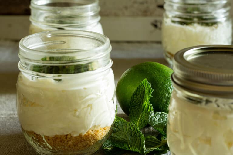 Jars of no bake cheesecake next to fresh mint and a lime