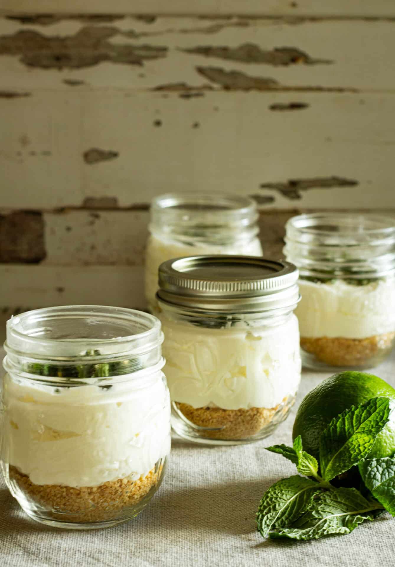 jars of no bake chhesecake with a lime and fresh mint