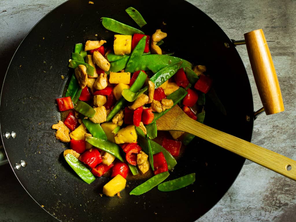 stir fry in a wok with a bamboo spatula