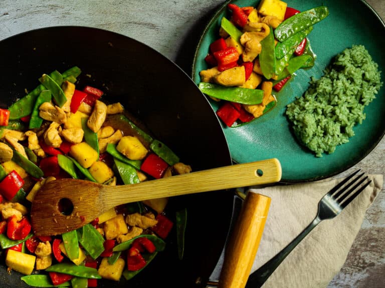 stirfry in a wok next to green bowm of stirfry with bamboo rice