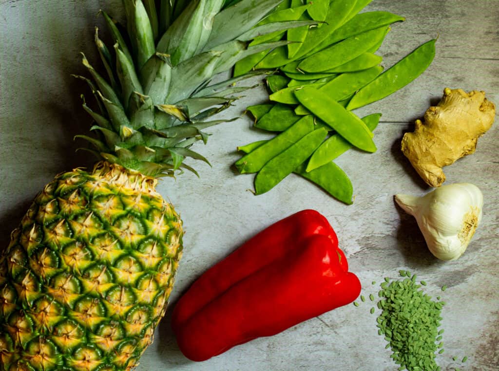 pineapple, ginger, a head of garlic, snow peas, red bell pepper, and bamboo rice