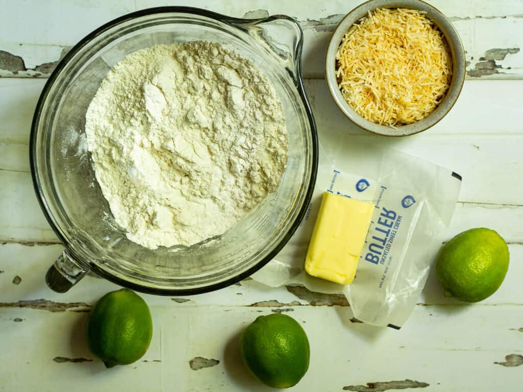 bowl of flour with butter, limes, and toasted coconut