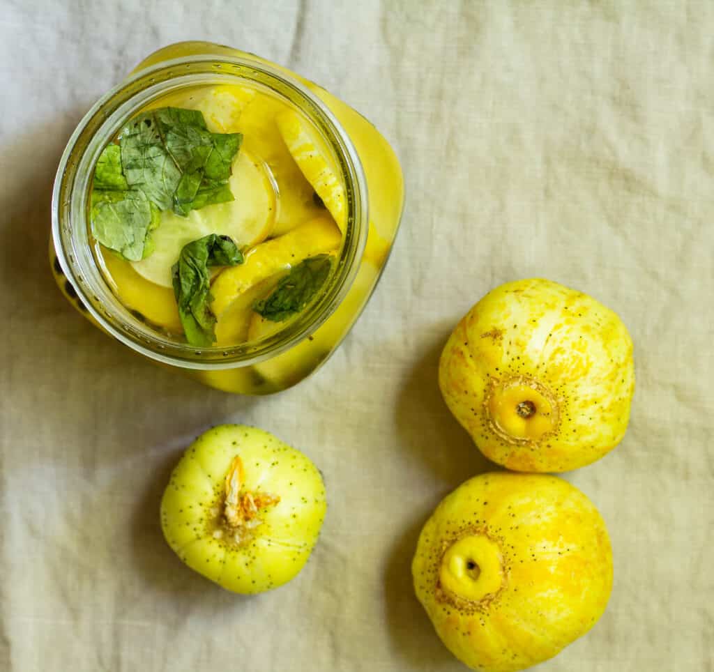 overhead view of a jar of lemon cucumber pickles with three lemon cucumbers