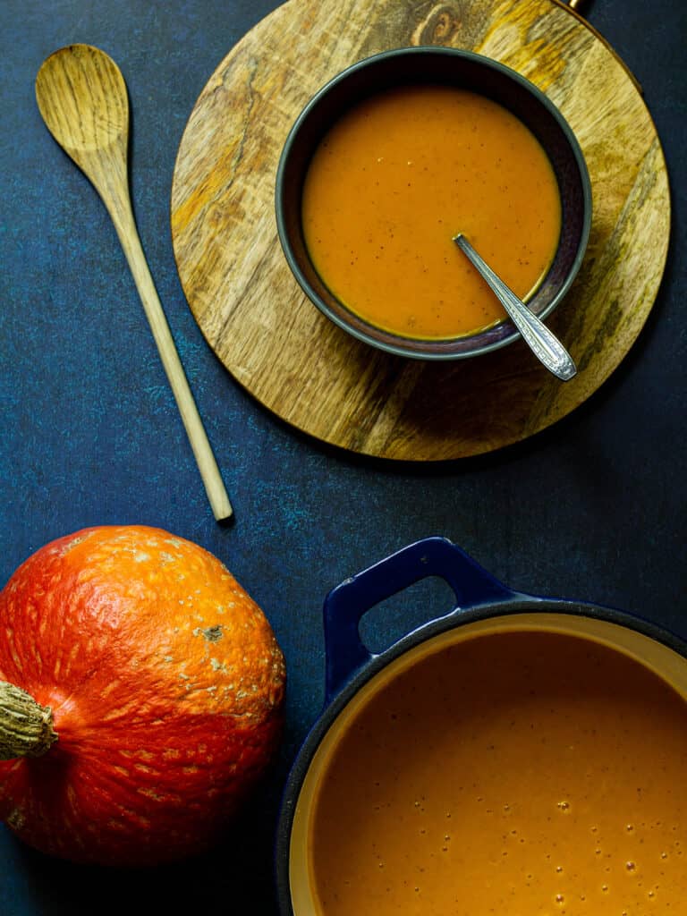 pot of squash soup with a wooden spoon and bowl of soup
