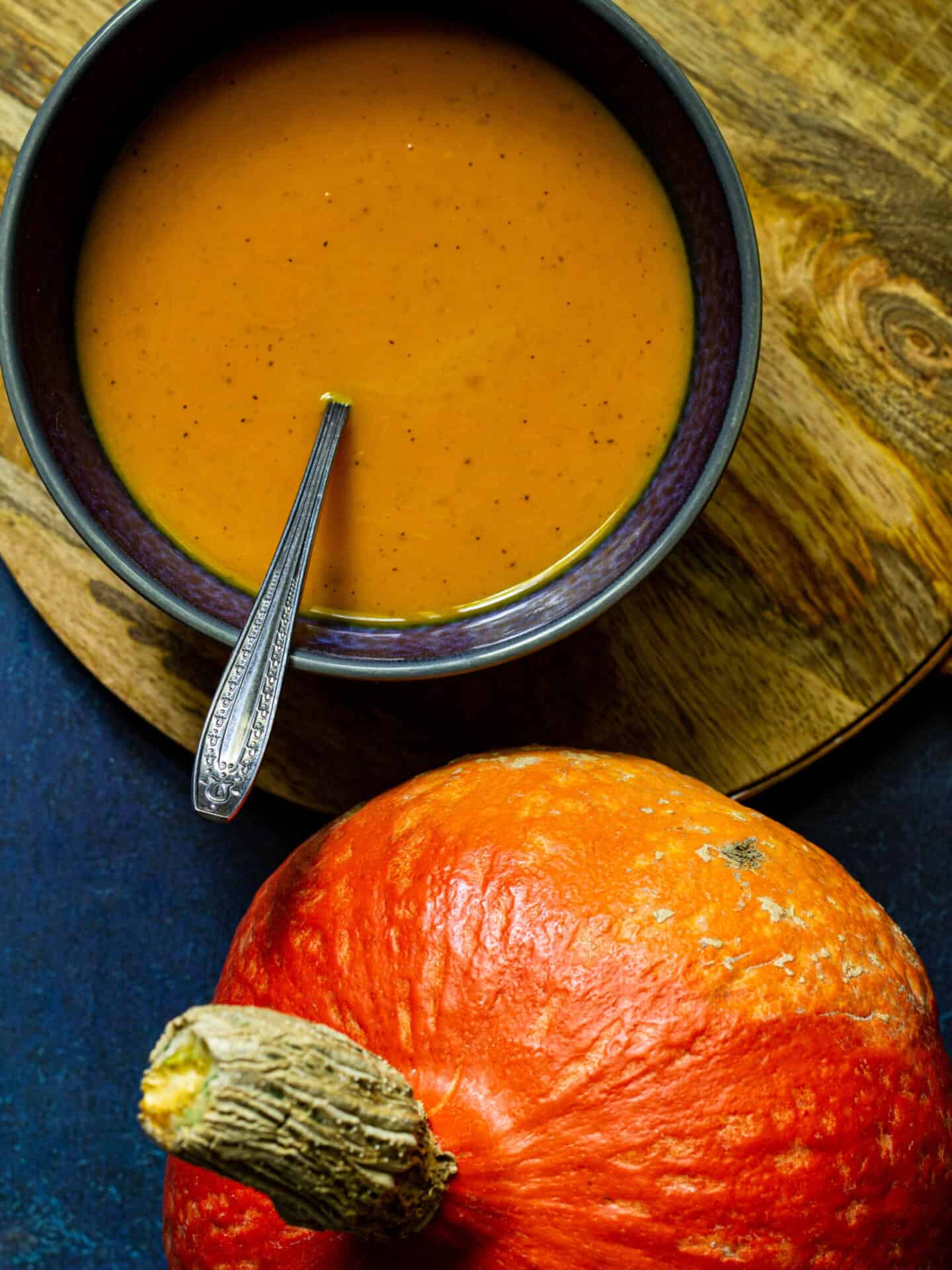 closeup photo of red kuri squash soup in a blue bowl