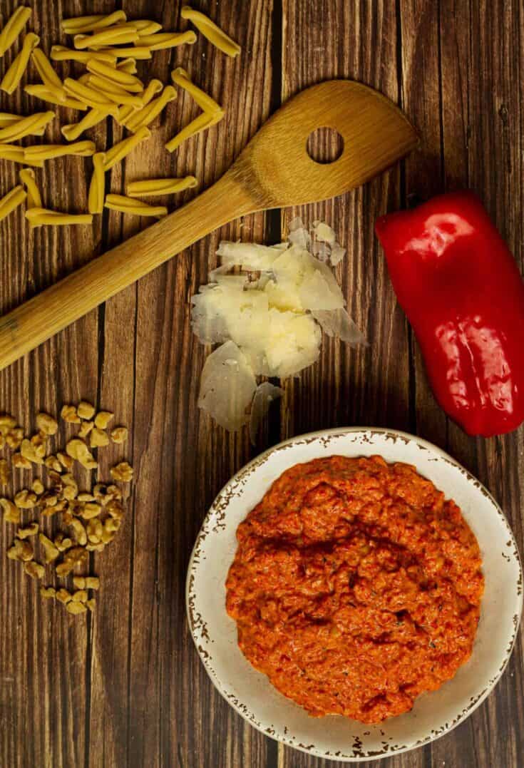 red pepper pesto with a wooden spoon and ingredients