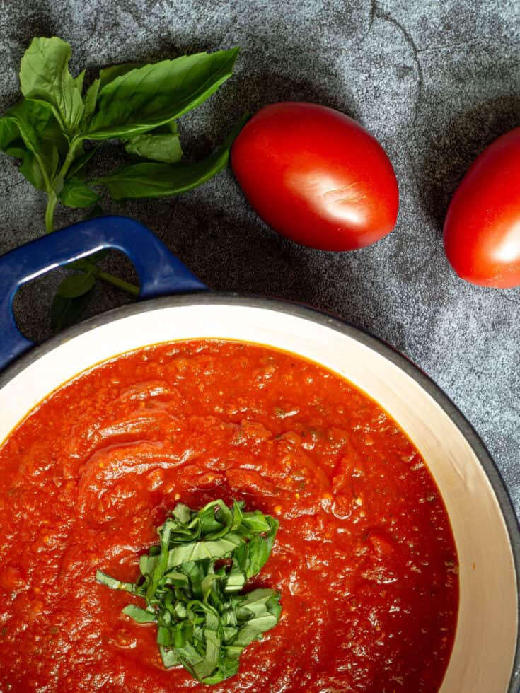 tomato sauce in a stock pot with fresh chopped basil