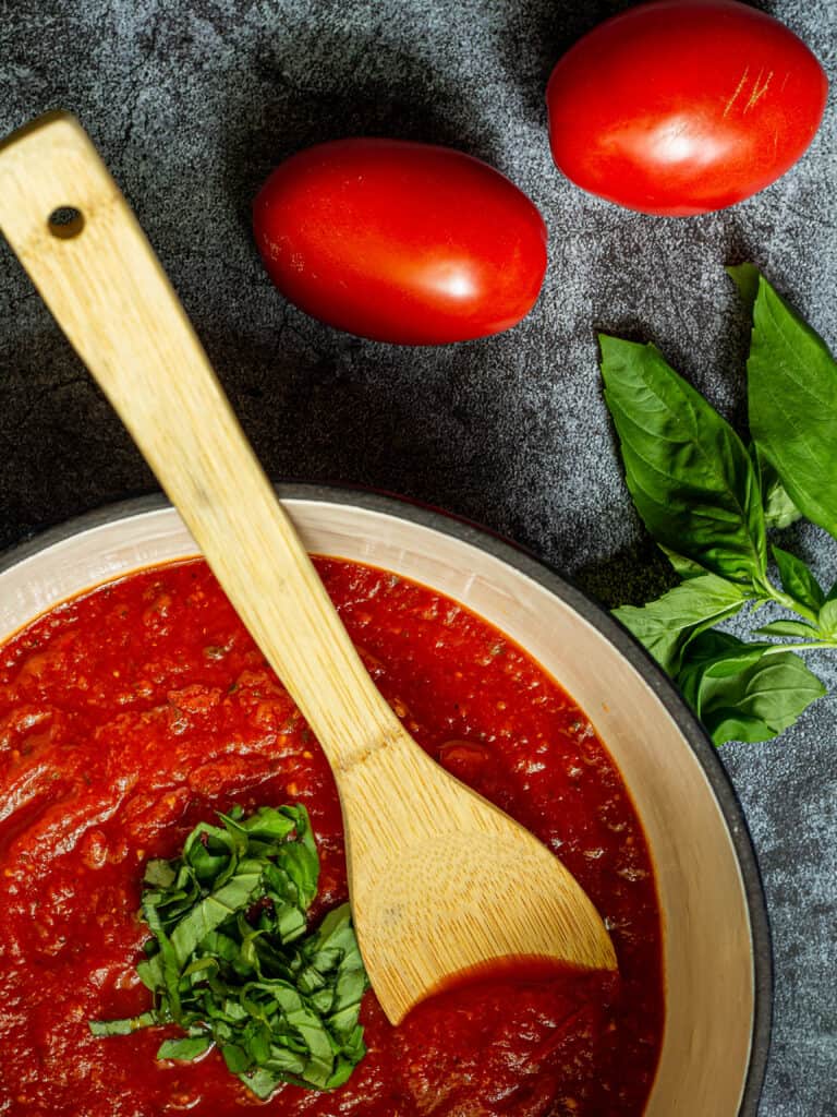 pot of marinara sauce with a wooden spoon on a blue background