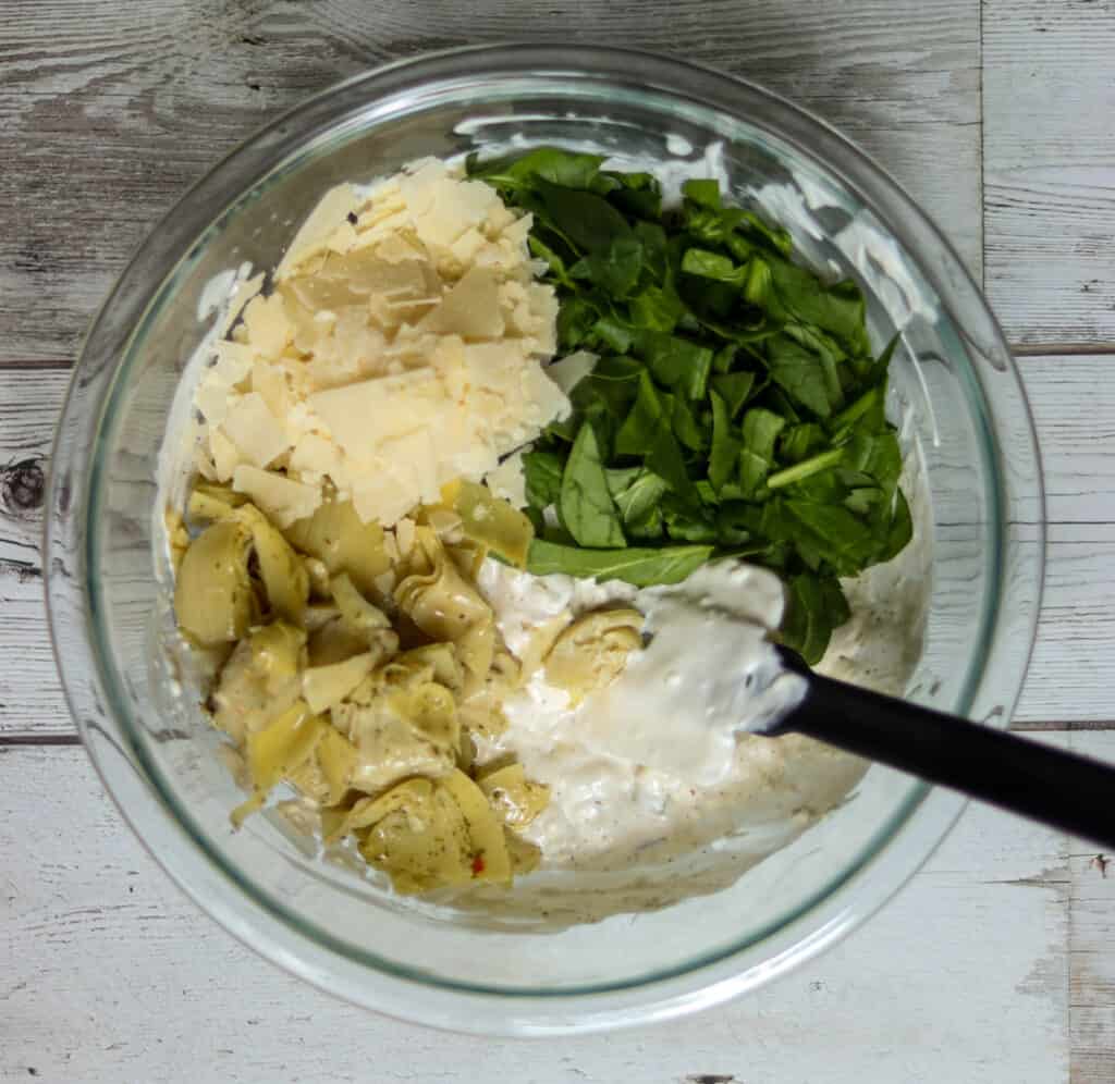Artichoke dip ingredients added to bowl