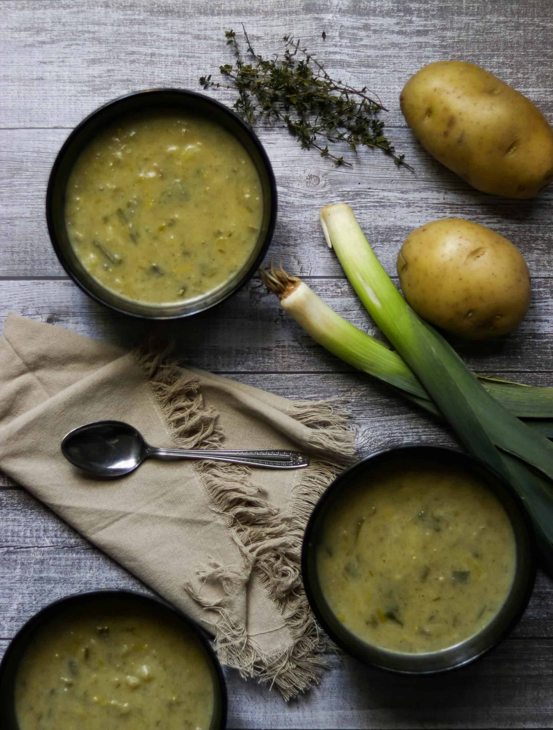 bowls of leek and potato soup with a napkin and spoon