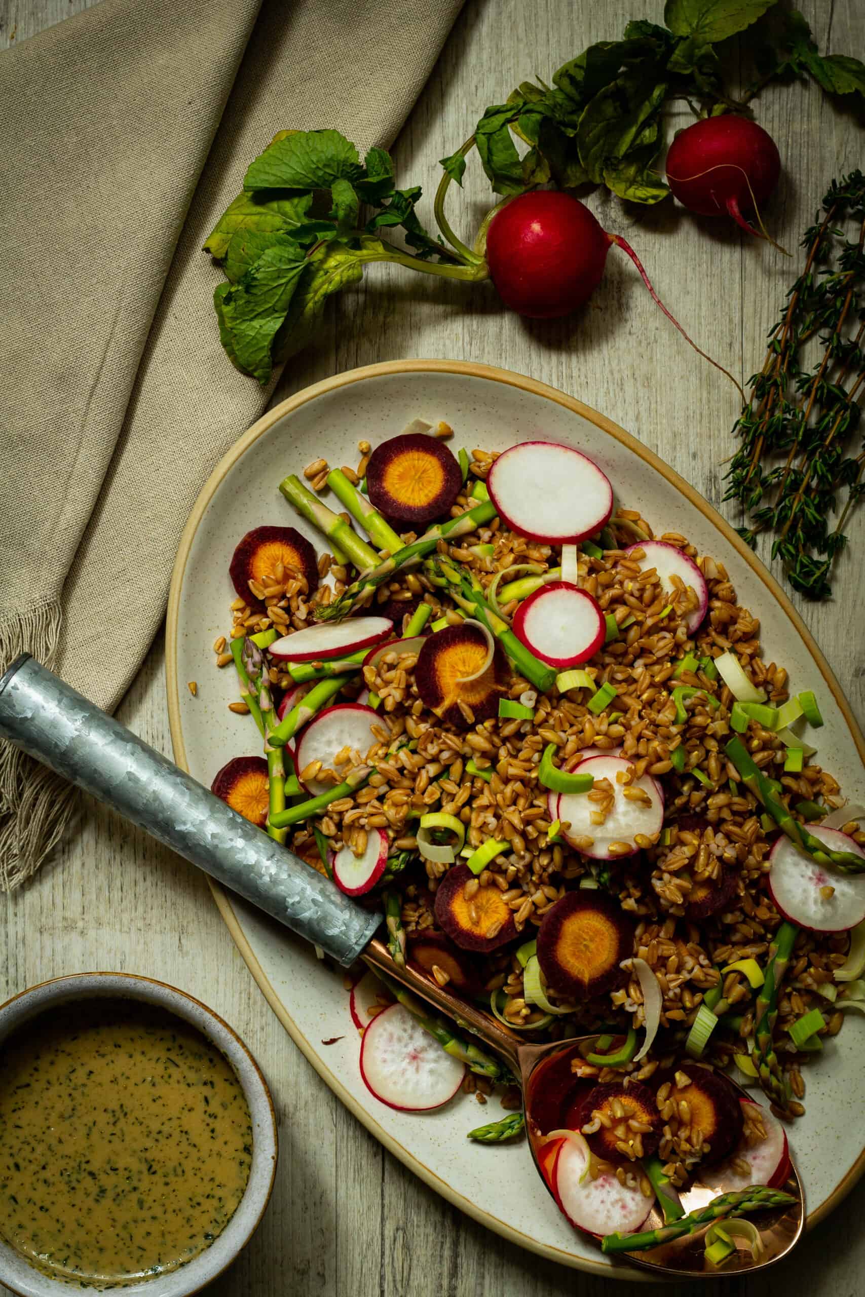 farro salad with a dish of vinaigrette and spoon