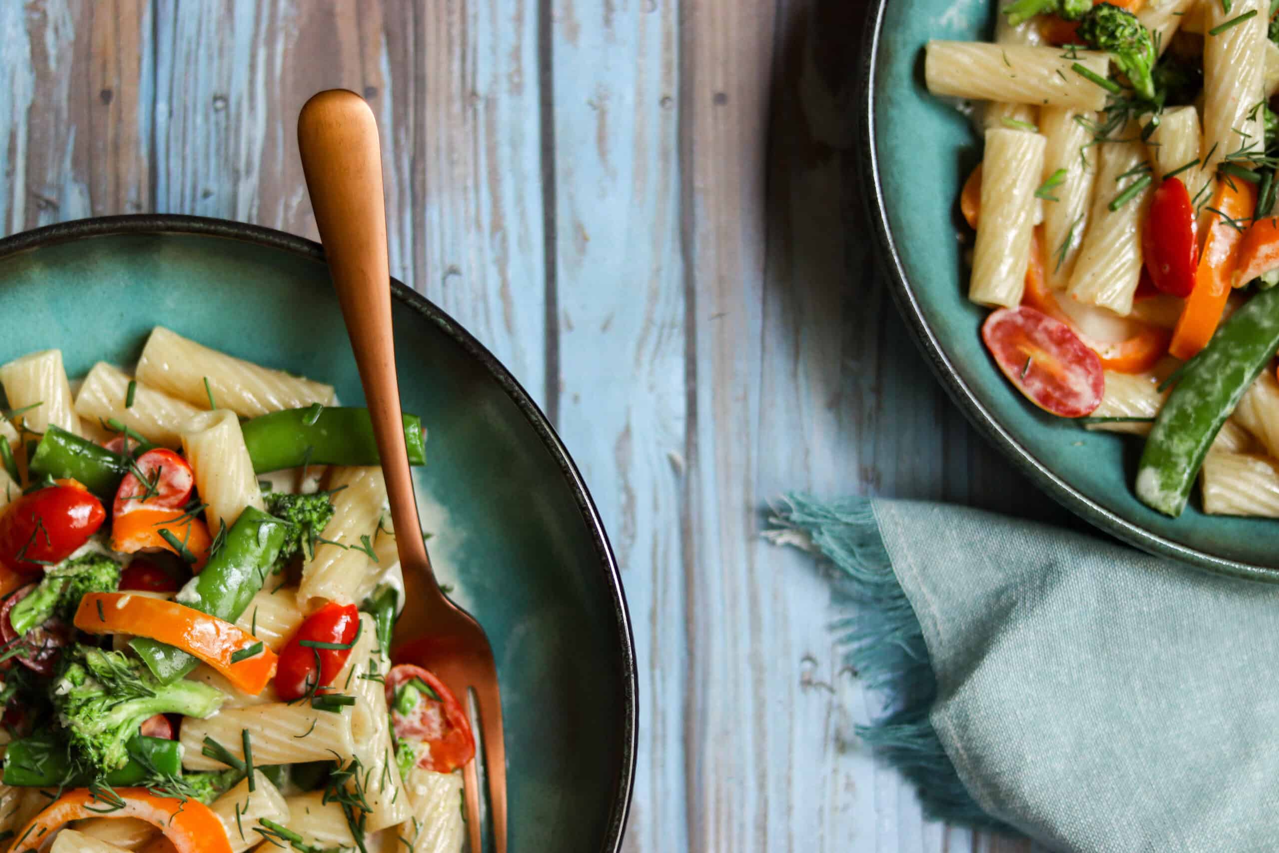 two bowls of rigatoni primavera with a fork