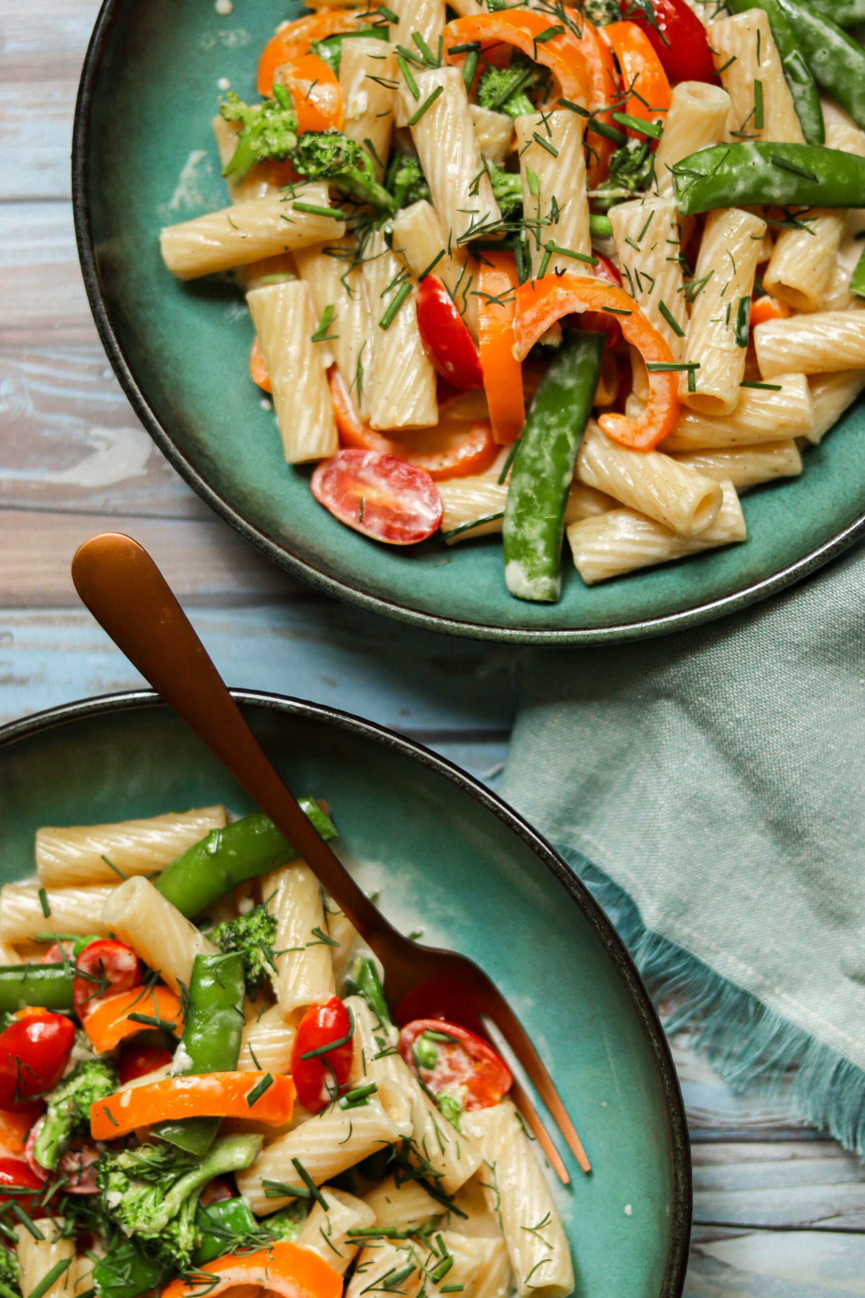 closeup photo of pasta and vegetables in blue bowls