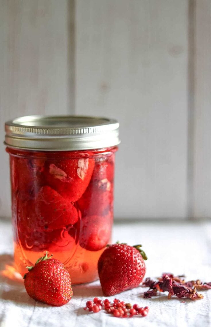 jar of pickled strawberries next to fresh srawberries