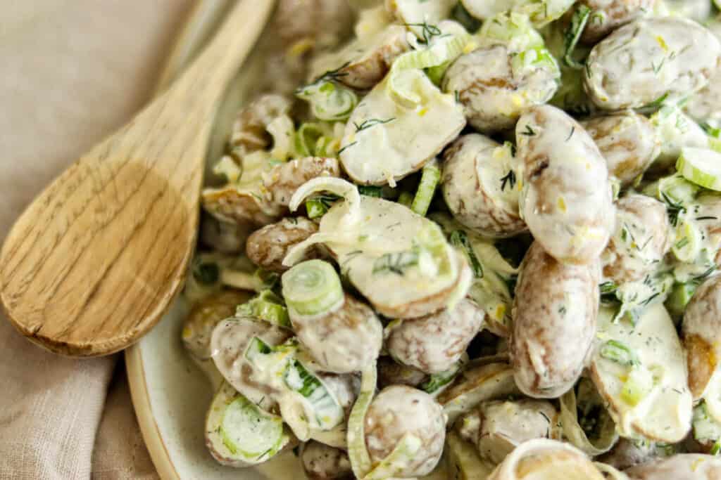 closeup photo of potato salad with a wooden spoon