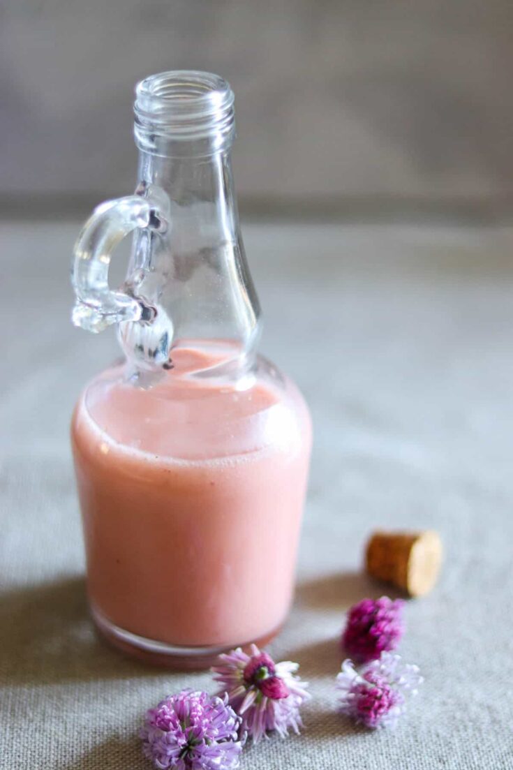 strawberry balsamic dressing in a glass bottle next to chive flowers