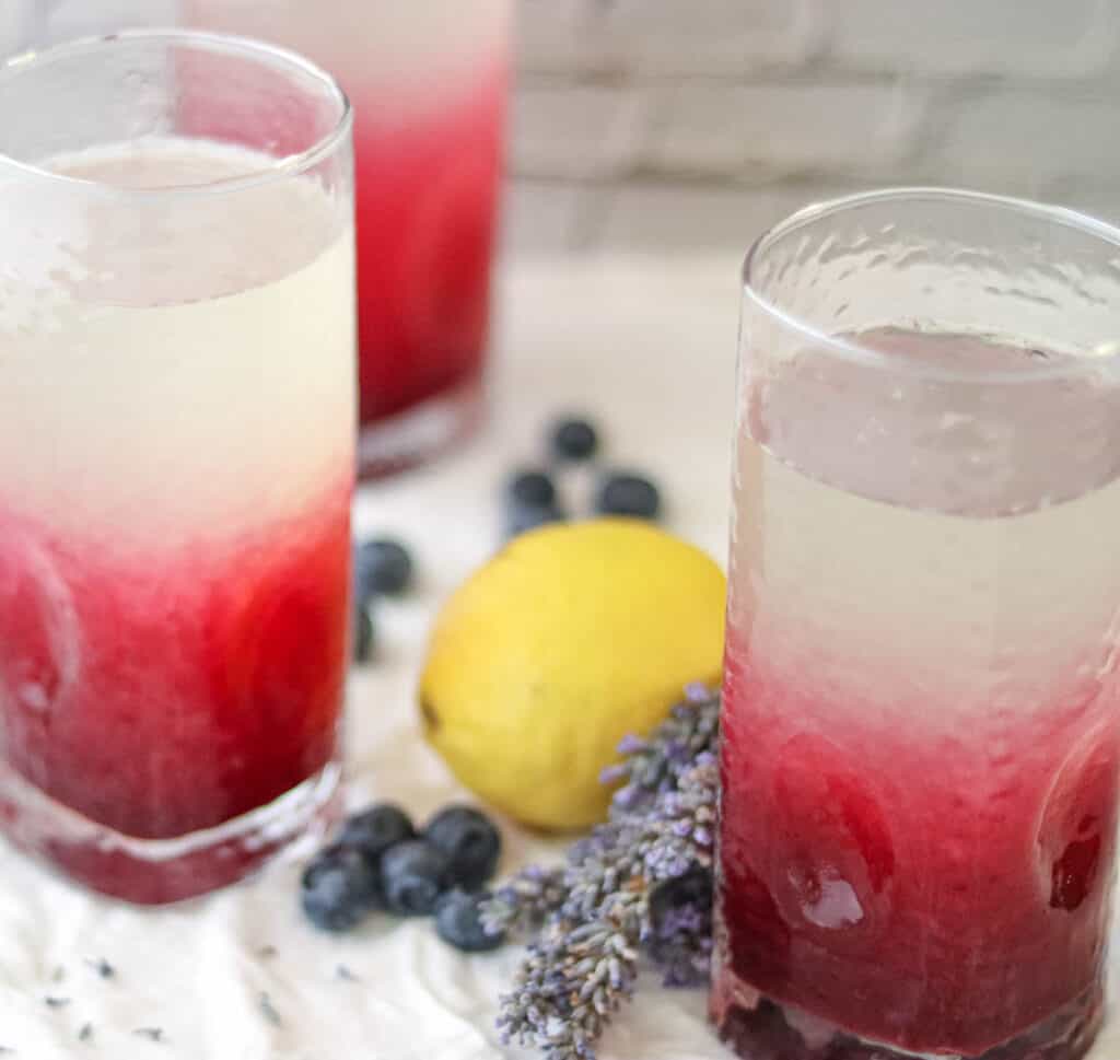 three glasses of lemonade with fresh blueberries and a lemon