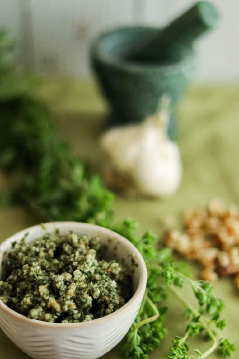 pesto in a small white bowl with oregano and garlic and walnuts