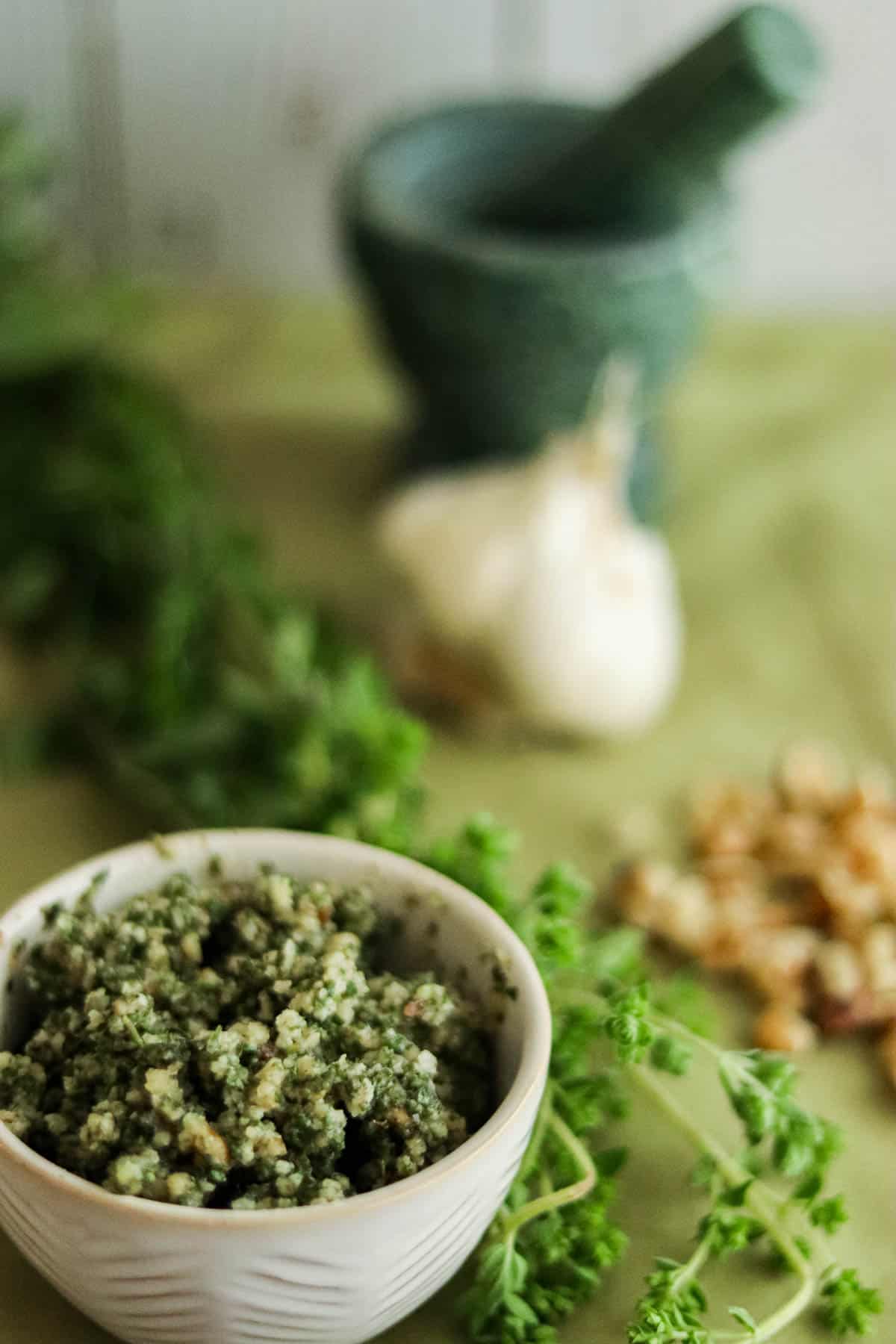 pesto in a small white bowl with oregano and garlic and walnuts