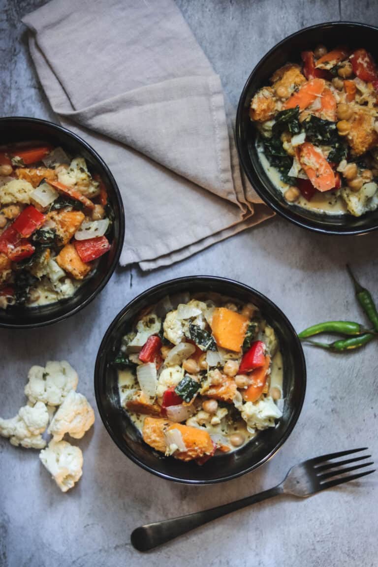three bowls of butternut squash curry with a wooden ladel.