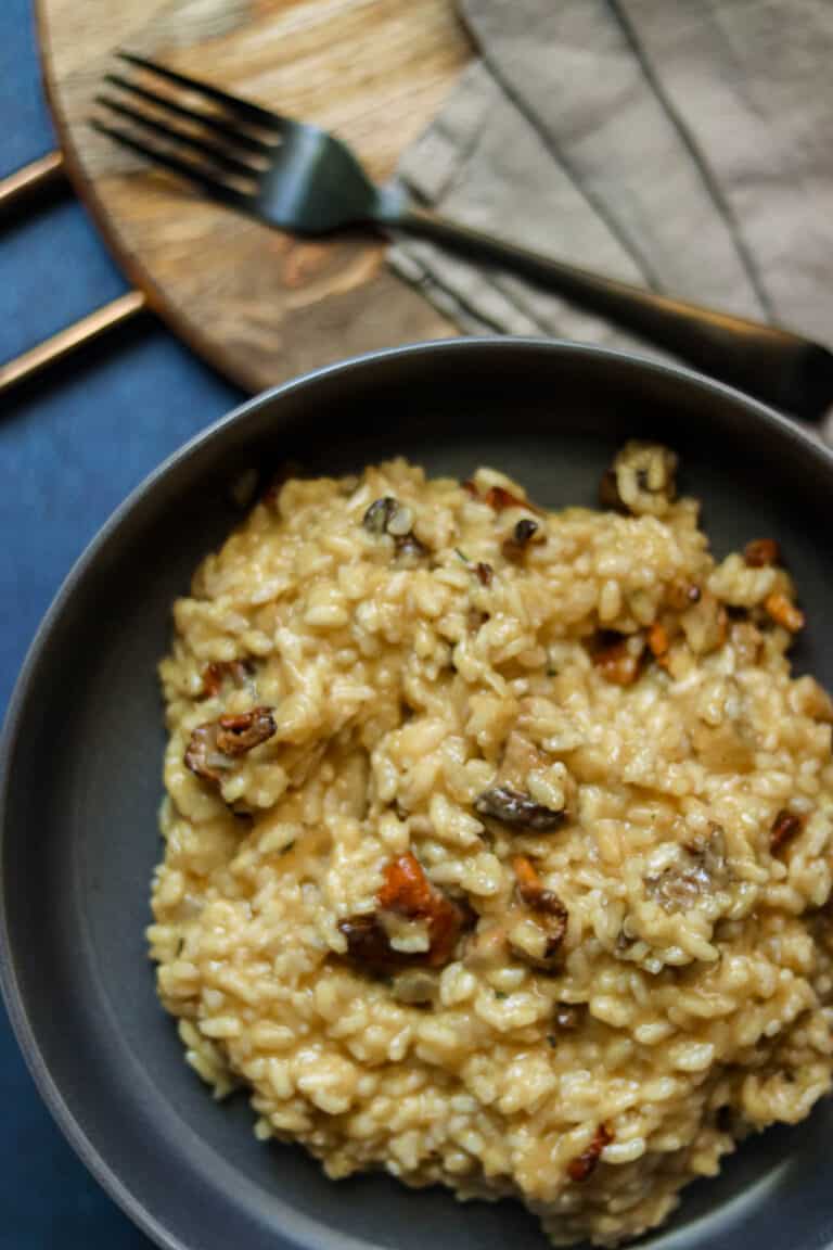 bowl of risotto on a blue background with a fork.