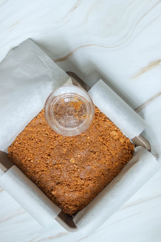 Pressing the gingersnap crumbs into the pan.