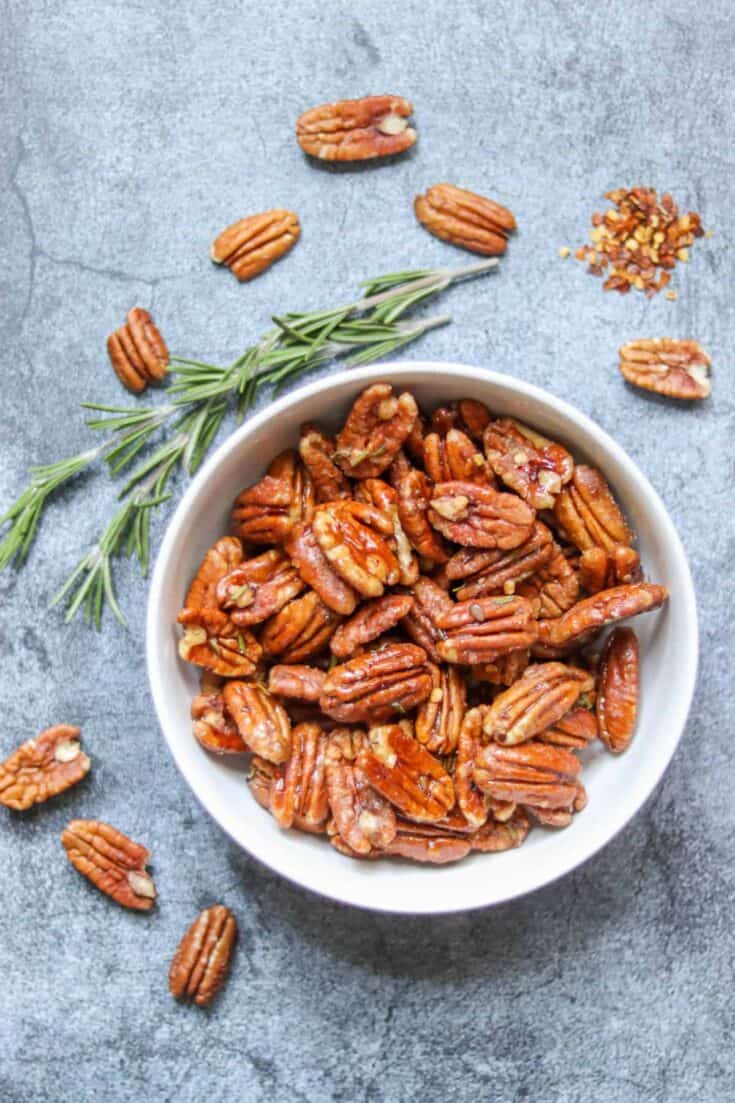 candied pecans in a bowl with fresh rosemary and red pepper flake