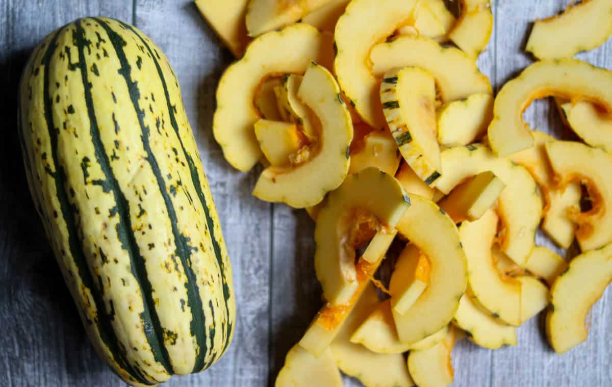 Whole Delicata Squash next to sliced Delicata Squash.