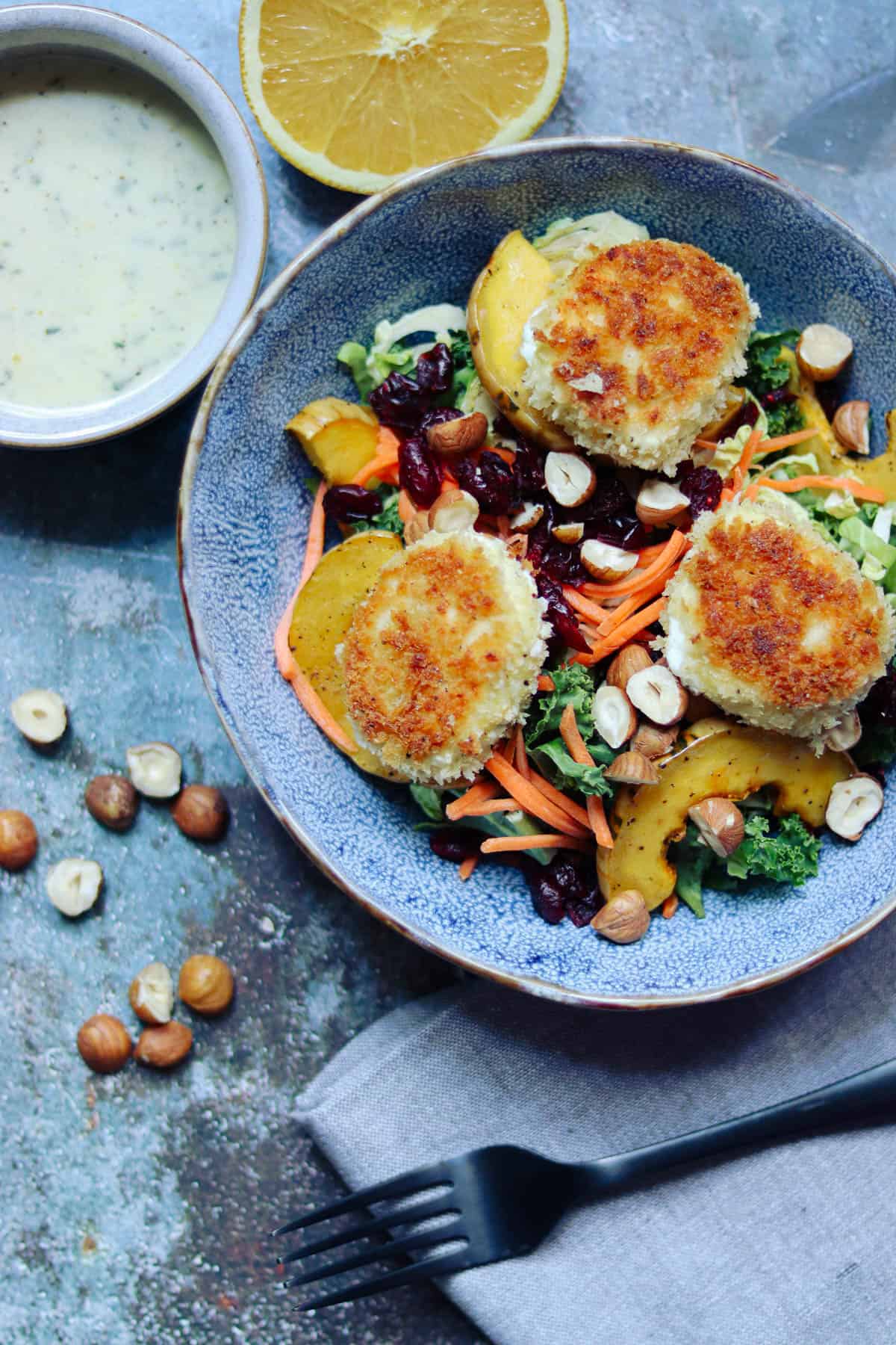 goat cheese salad in a blue bowl with a cup of vinaigrette.