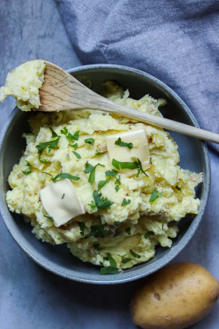 mashed potatoes in a bowl with a wooden spoon.