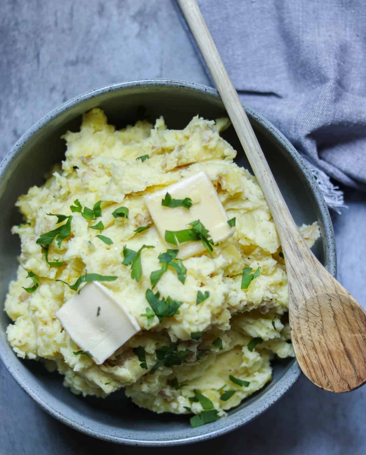 mashed potatoes topped with butter in a gray bowl.