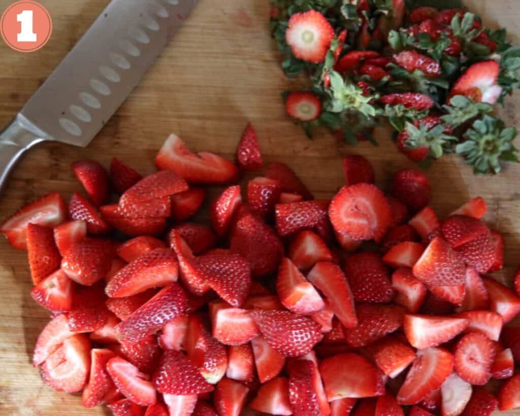 Cut Strawberries on a wooden cutting board.