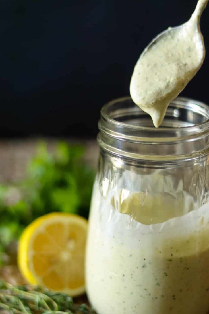 Lemon Herb Tahini Sauce in a jar with a spoon.
