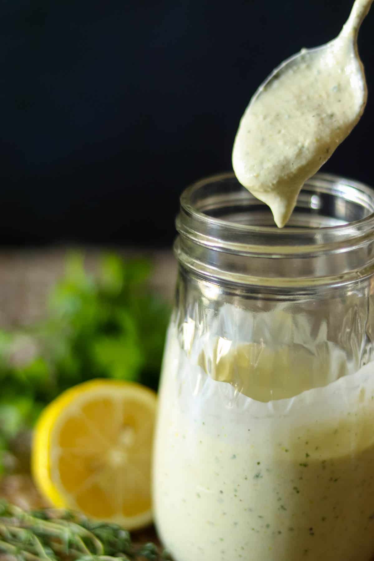 Lemon Herb Tahini Sauce in a jar with a spoon.