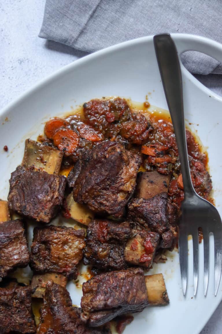 Short ribs with the cooked aromatics with a silver fork.