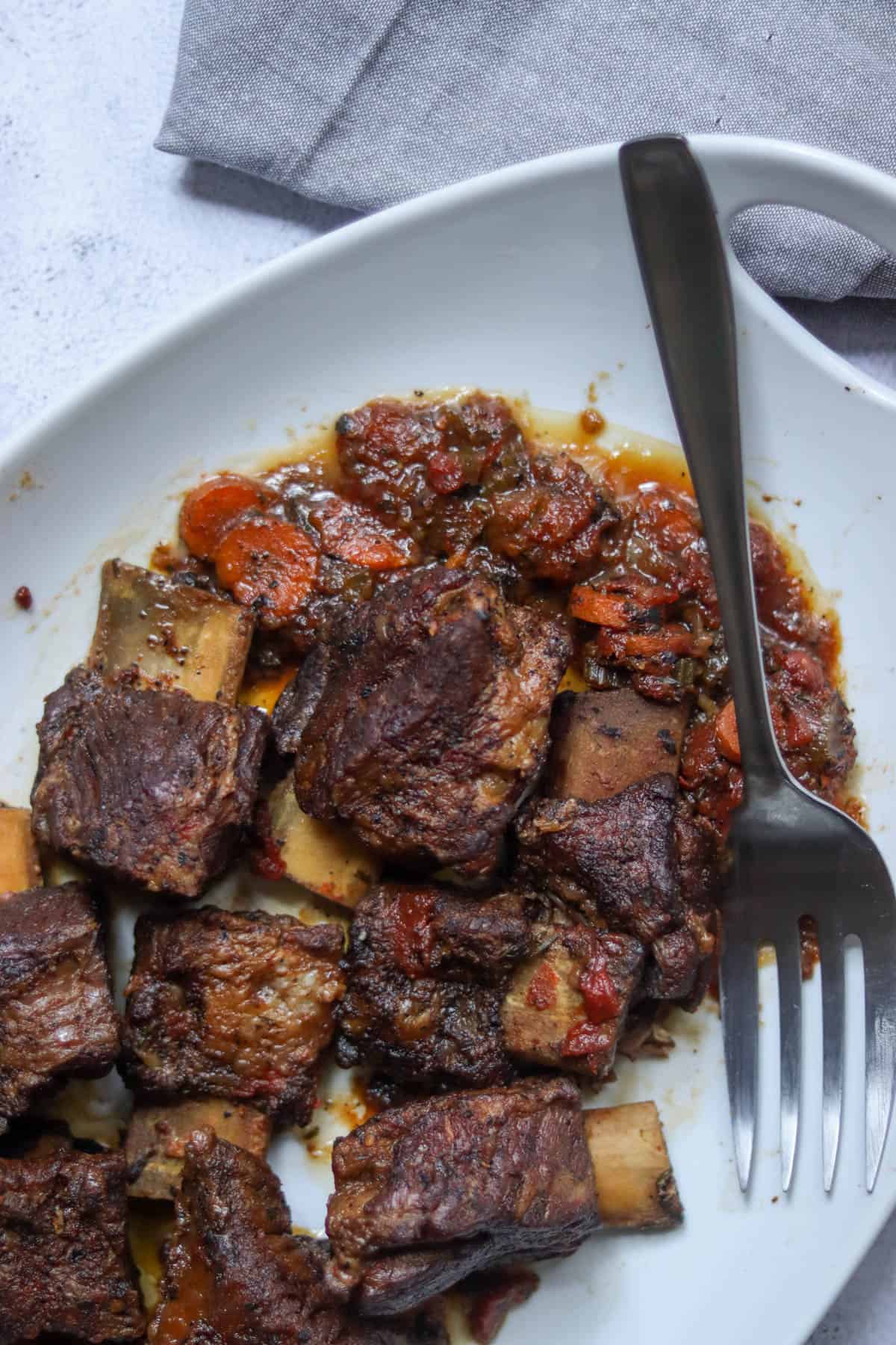 Short ribs with the cooked aromatics with a silver fork.