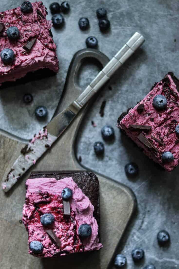 three pieces of cake on a wooden board with a knife.