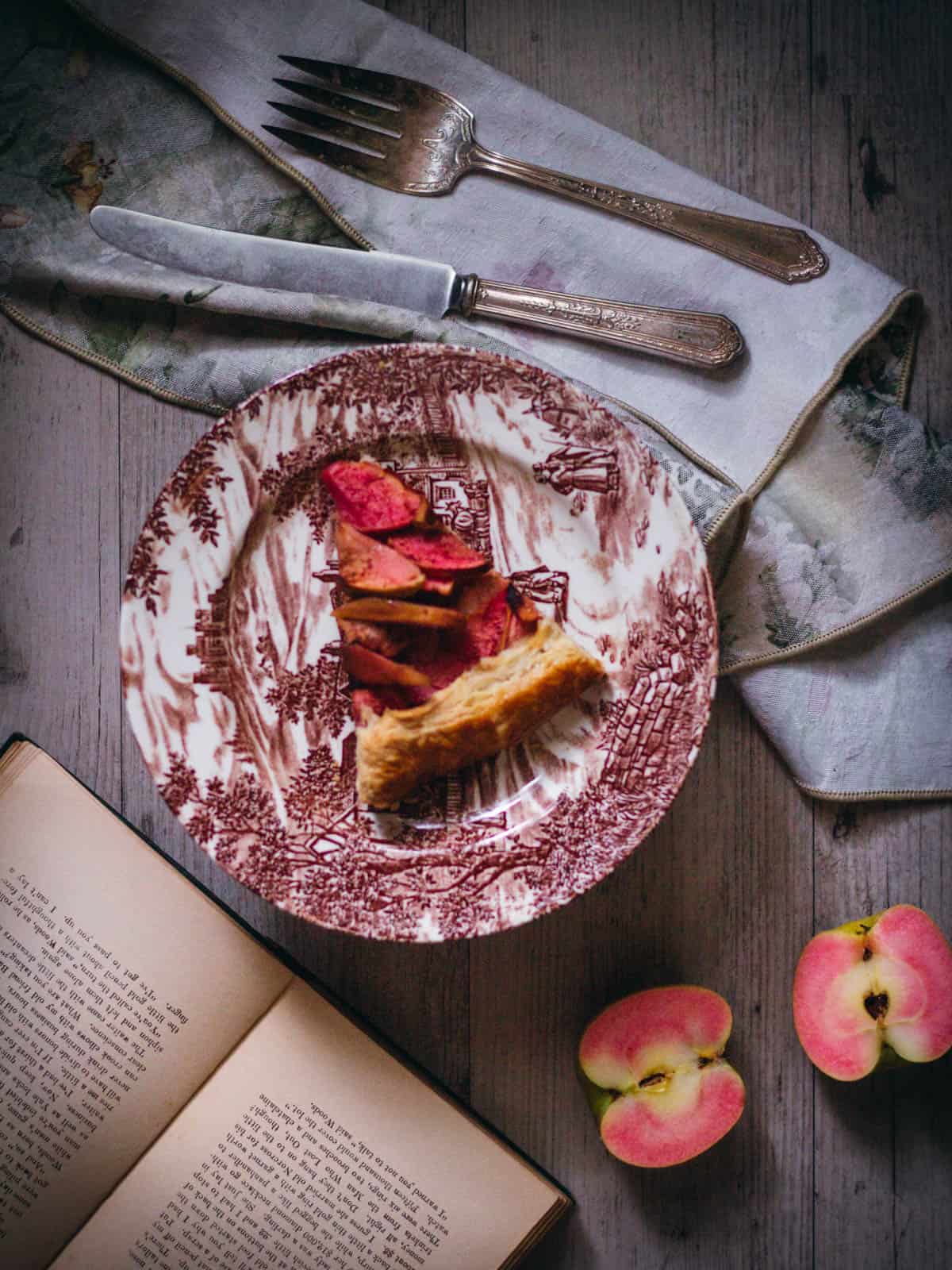 Galette slice on a plate with a cut apple beside it.