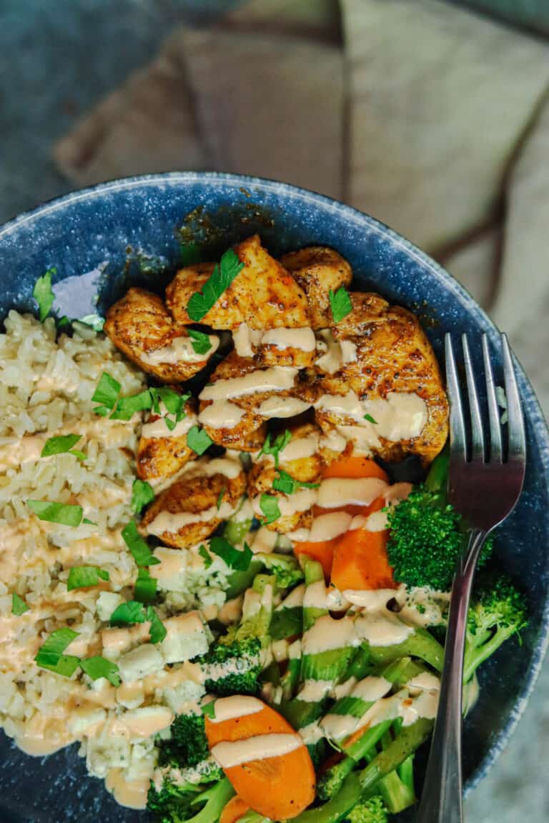 Buffalo chicken, vegetables, and rice in a blue bowl.