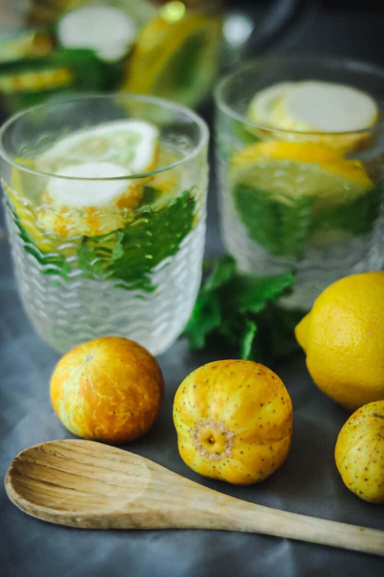 two glasses of lemon cucumber water with a spoon.