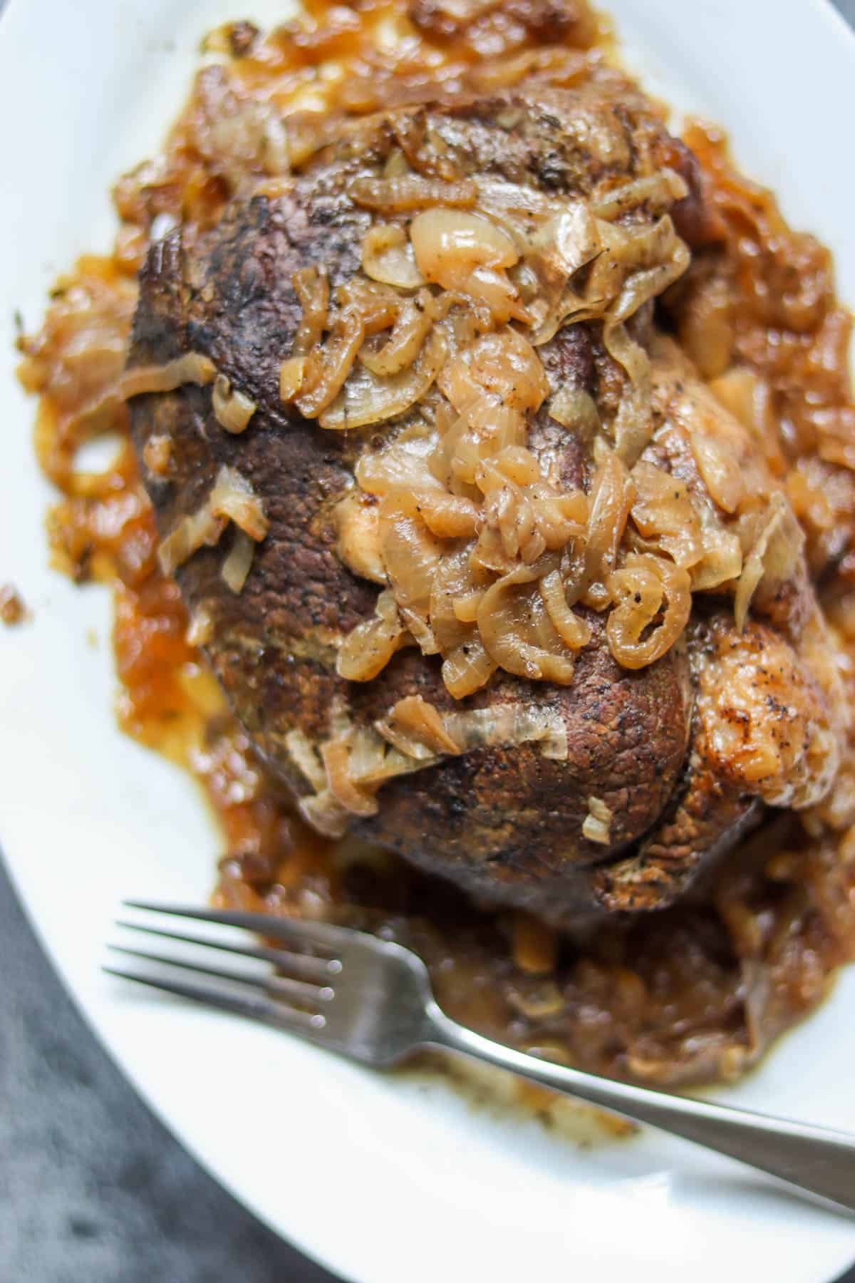 Pot Roast with onions on a white plate.
