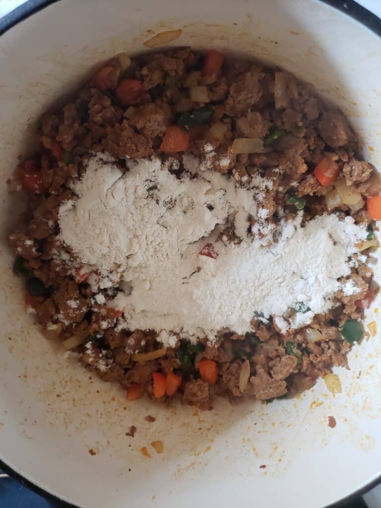Add flour to the meat and vegetables to make a roux.