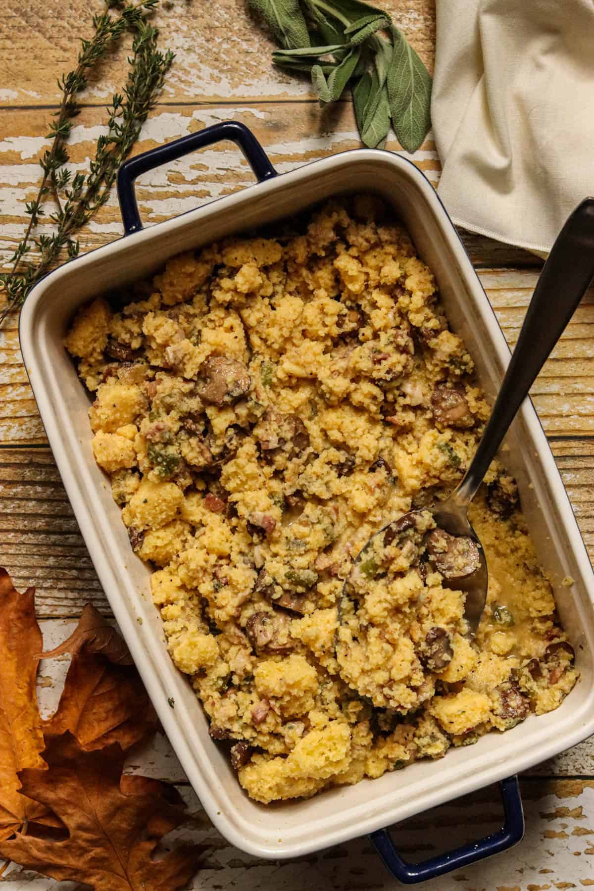 Casserole dish of cornbread dressing with fresh herbs.