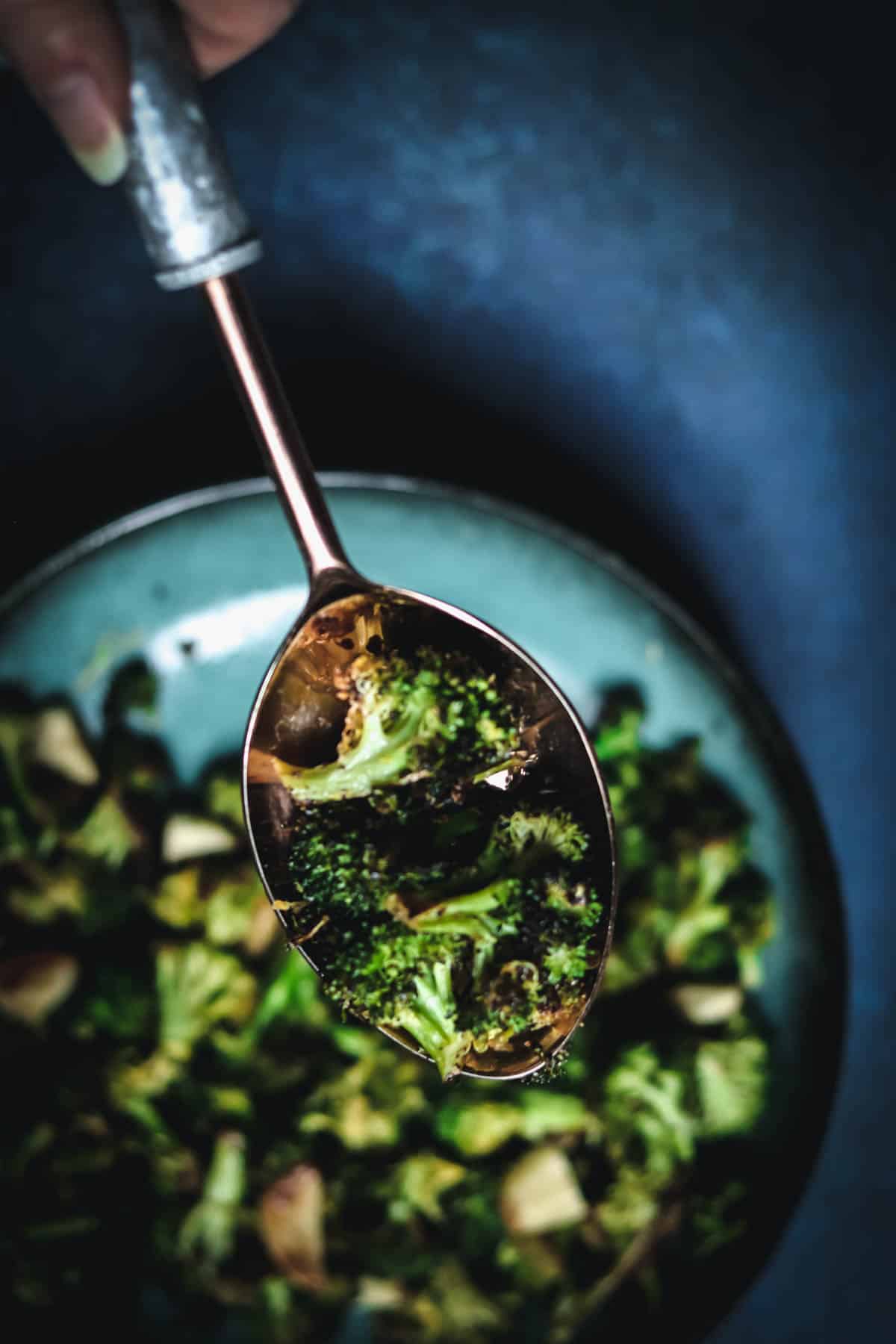 Charred broccoli on a large spoon.