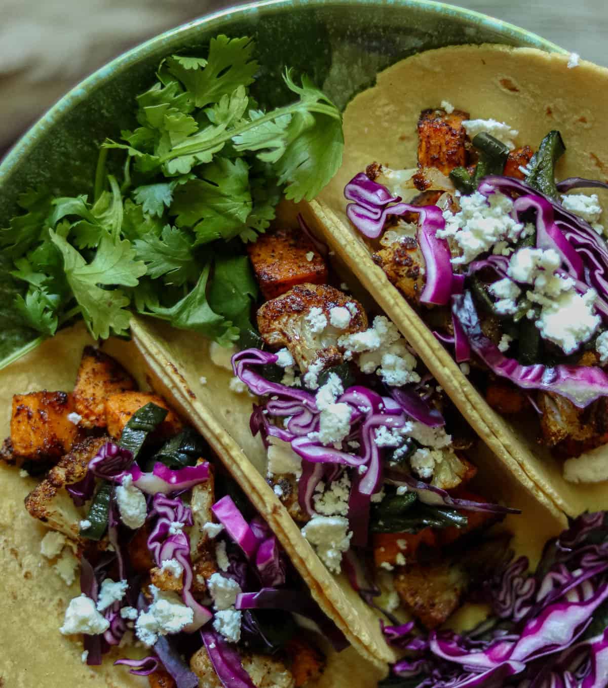 Cauliflower sweet potato tacos in a green dish.